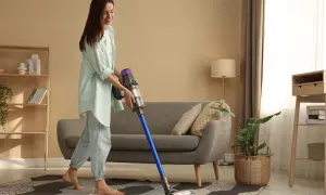 Kobieta sprząta salon odkurzaczem Dyson.