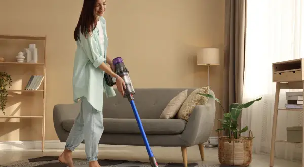 Kobieta sprząta salon odkurzaczem Dyson.